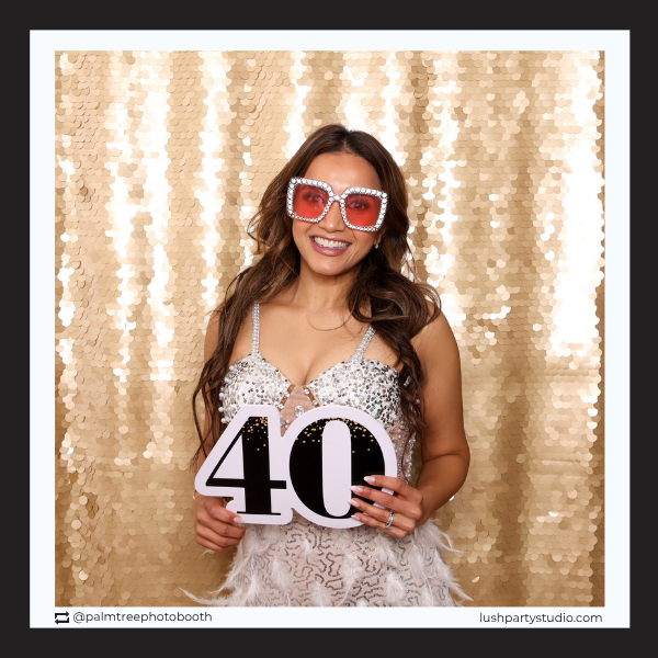 Woman in a sequin dress holding a '40' photo booth prop sign by lush party studio