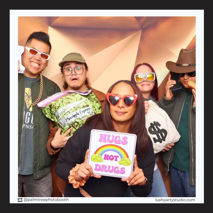 Group of people posing with props and a prop sign that reads 'Hugs Not Drugs' at a photo booth.