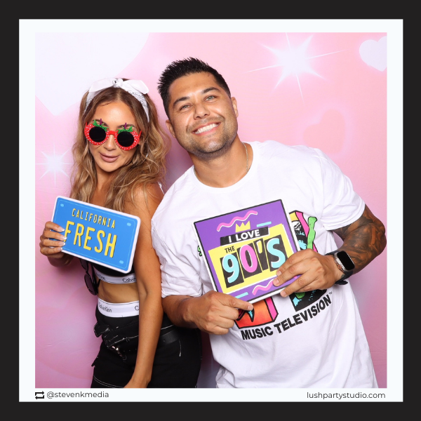 Two people posing with 90s themed prop signs by Lush Party Studio