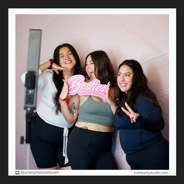 Three women posing with a 'Besties' photo booth prop sign by Lush Party Studio