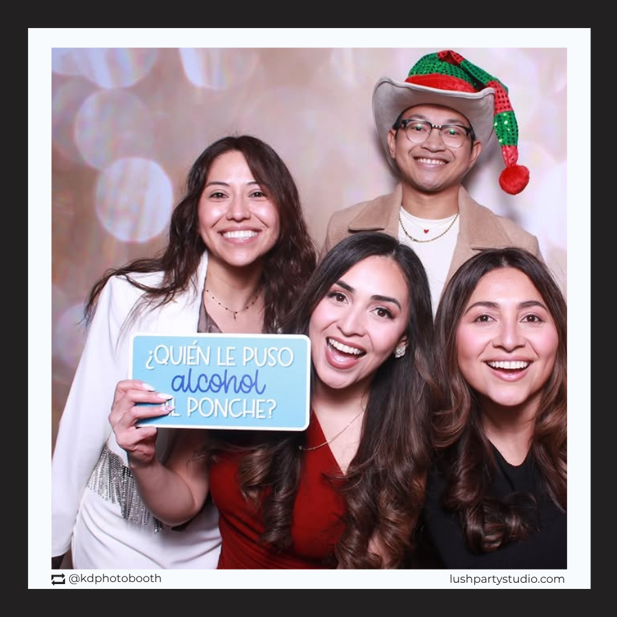 Four people posing with a photo booth prop sign by lush party studio