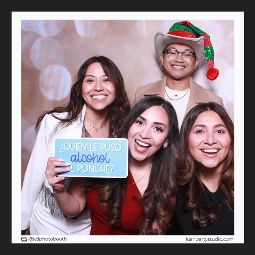 Four people posing with a photo booth prop sign by lush party studio