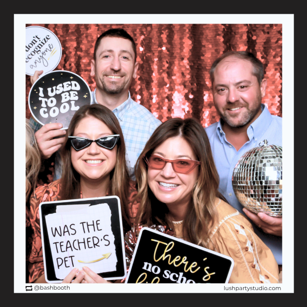 Group of people posing with class reunion photo booth props by lush party studio