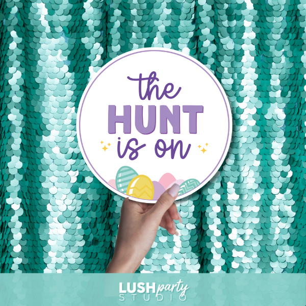 Hand holding a sign with 'The Hunt is On' text for Easter events and parties egg hunts and religious easter by Lush Party Studio 