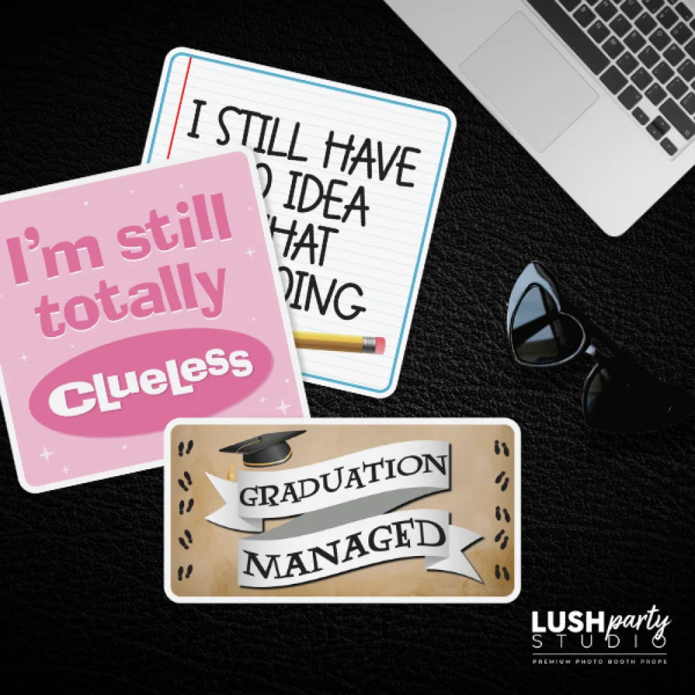 Three funny sayings for grads, graduation photobooth props by lush party studio on a dark surface with a laptop and sunglasses.