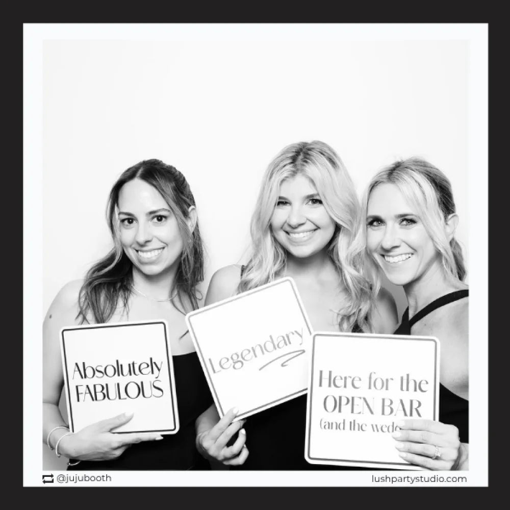 photo booth prop signs with party phrases in a black and white photo 