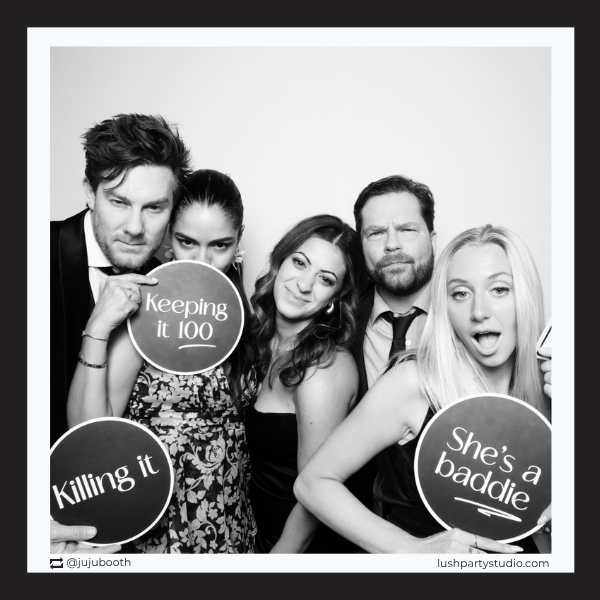 Group of people posing with glam vogue photo booth prop signs