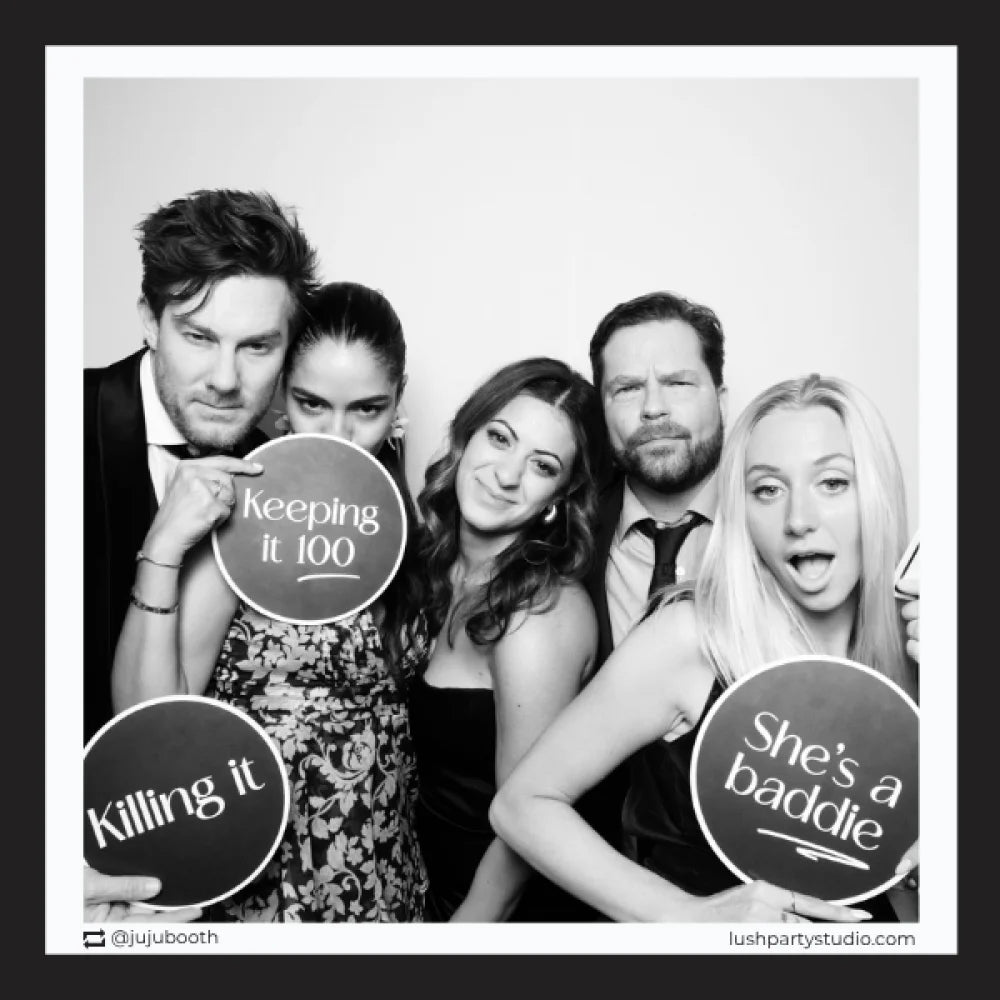 Group of people posing with glam vogue photo booth prop signs