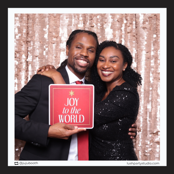 couple holding a joy to the world photobooth prop