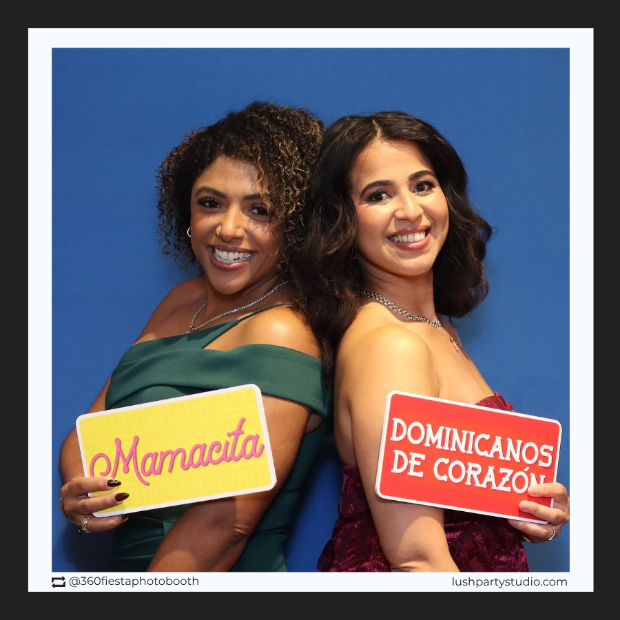 Two women holding photo booth prop signs with Spanish party text