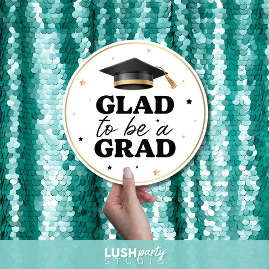 Graduation-themed photobooth prop sign with 'GLAD to be a GRAD' text by lush party studio