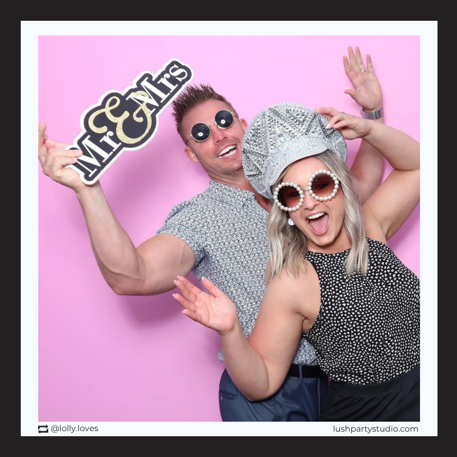 Two people posing with a wedding mr and mrs photo booth prop sign by lush party studio