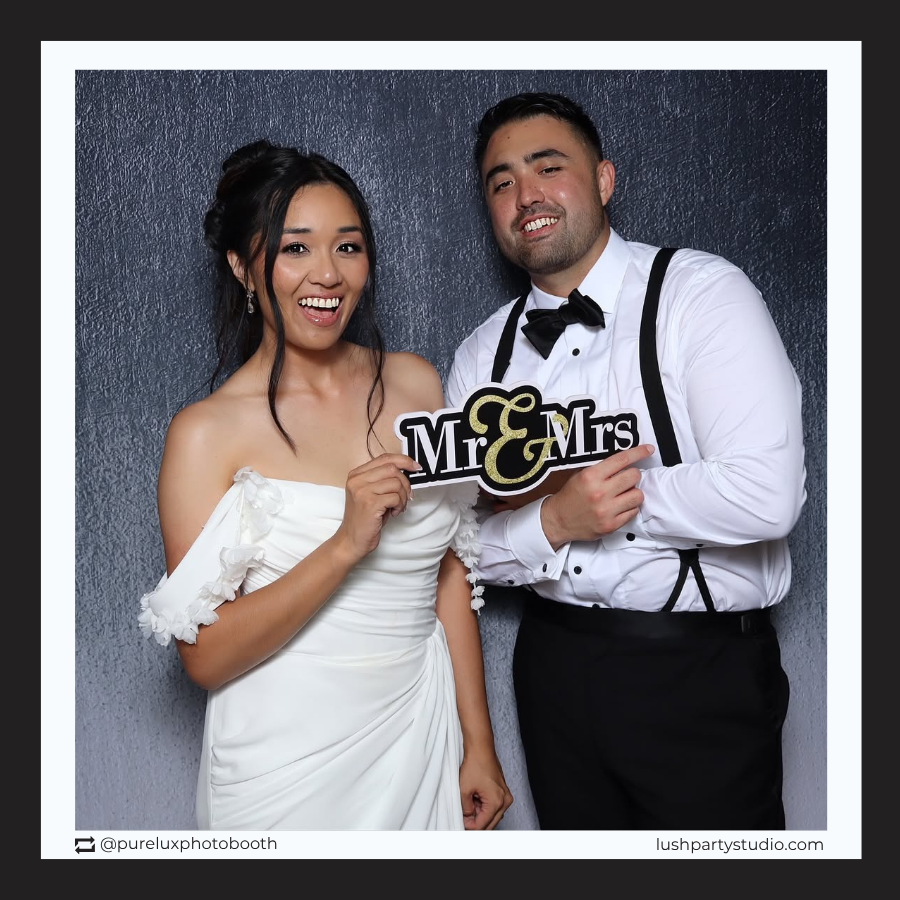 Two people posing with a wedding mr and mrs photo booth prop sign by lush party studio