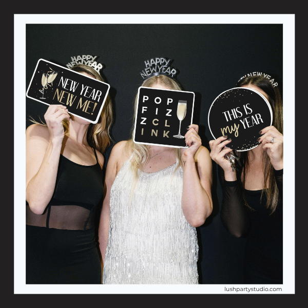 Three women holding New Year's Eve-themed prop signs