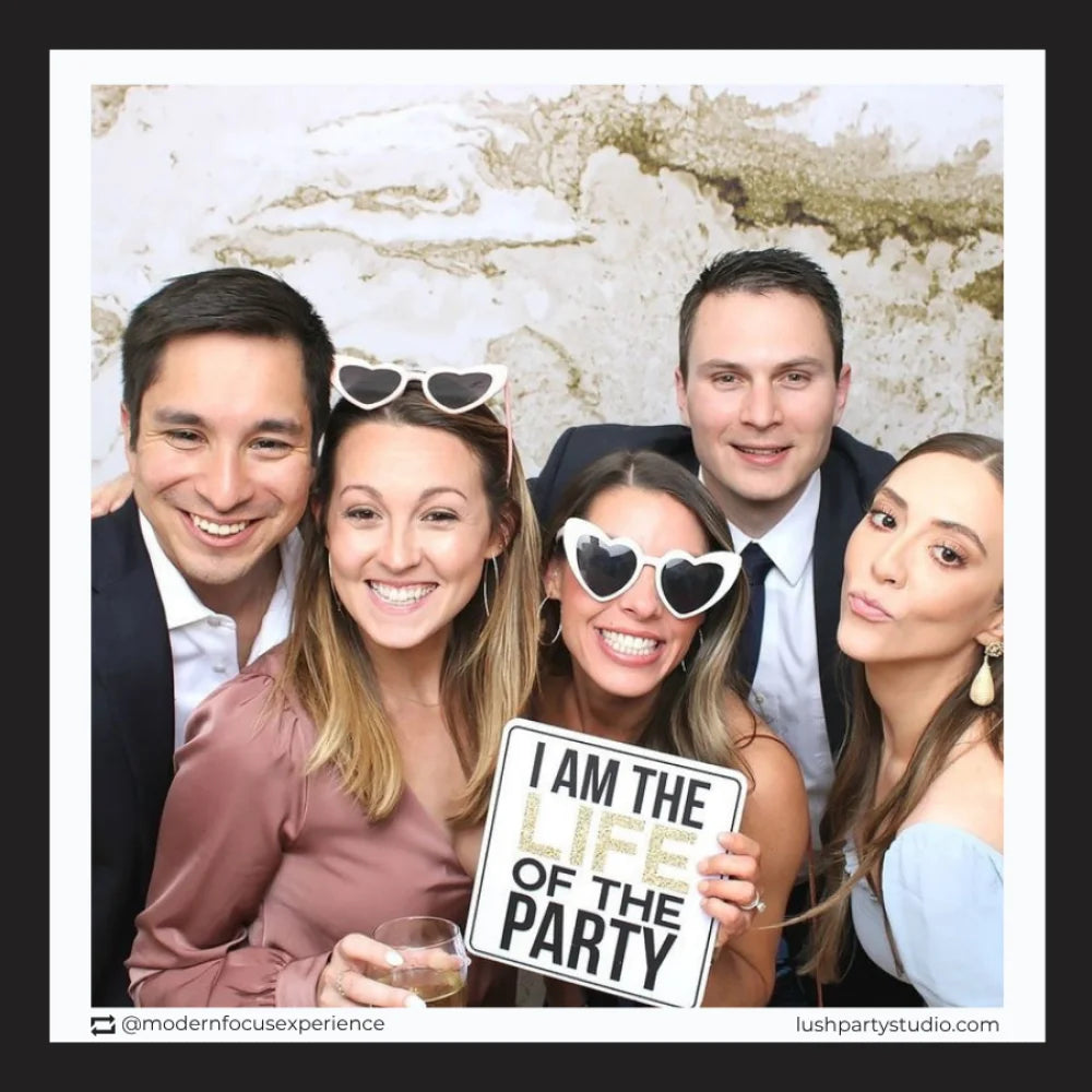 Group of people posing with photo booth prop sign that reads 'I am the life of the party' 