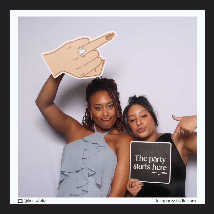 engagement ring finger photo booth prop by lush party studio and a sign saying 'The party starts here' against a plain background.