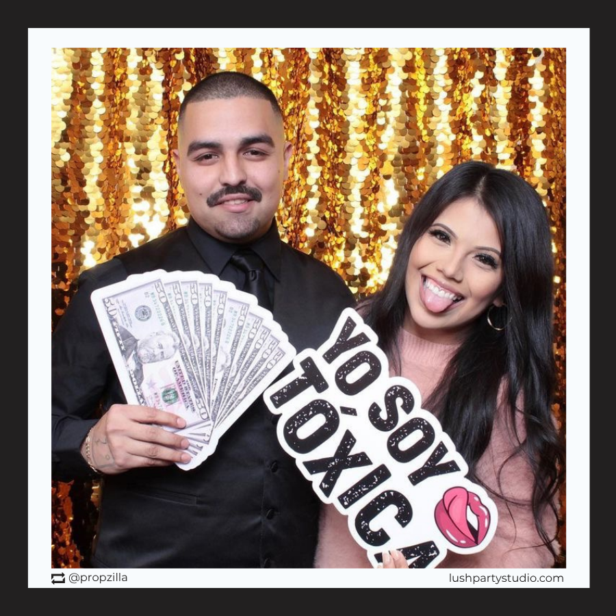 Two people posing with toxica photo booth prop sign by lush party studio