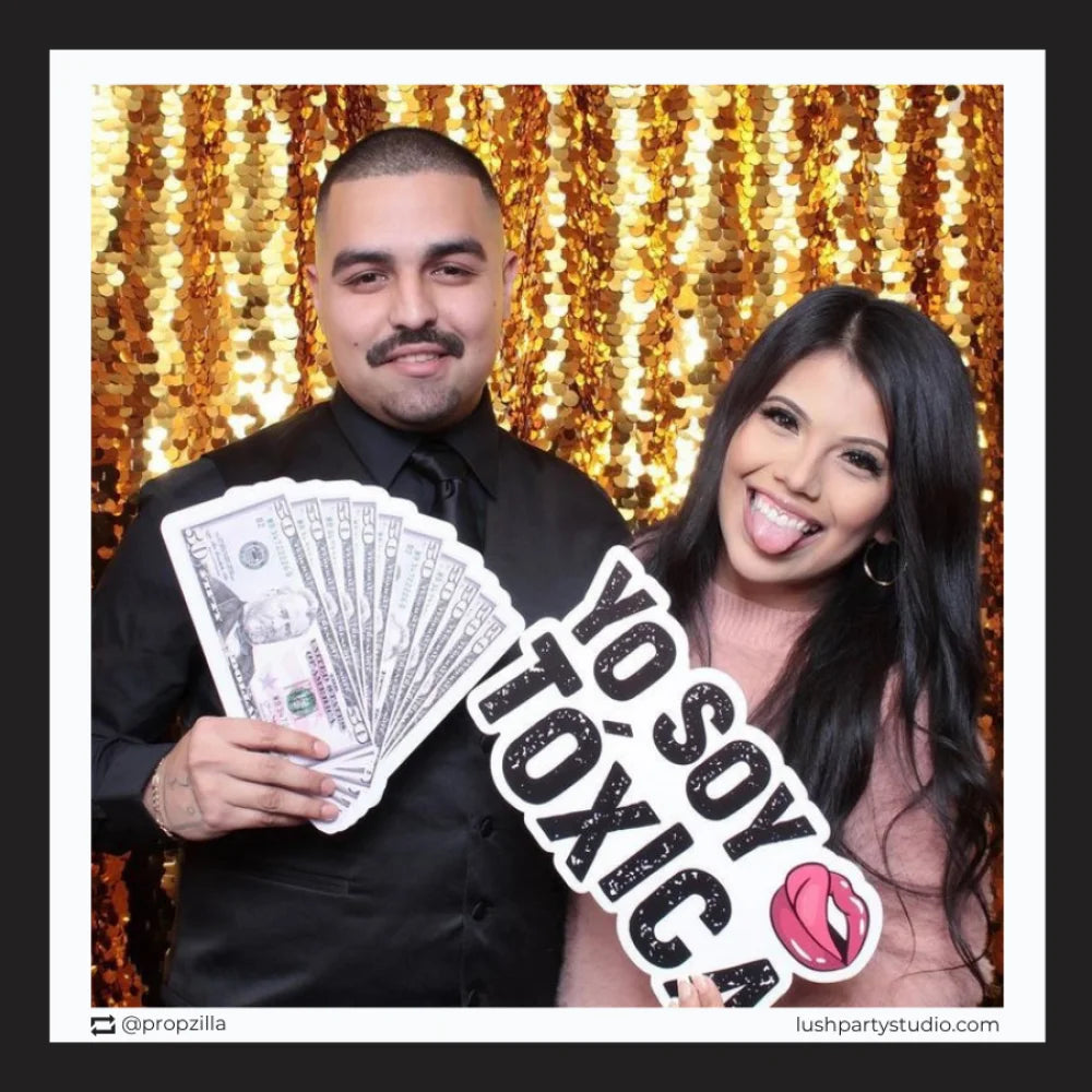 Two people posing with toxica photo booth prop sign by lush party studio