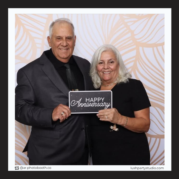 Man and woman holding a 'Happy Anniversary' sign by lushpartystudio