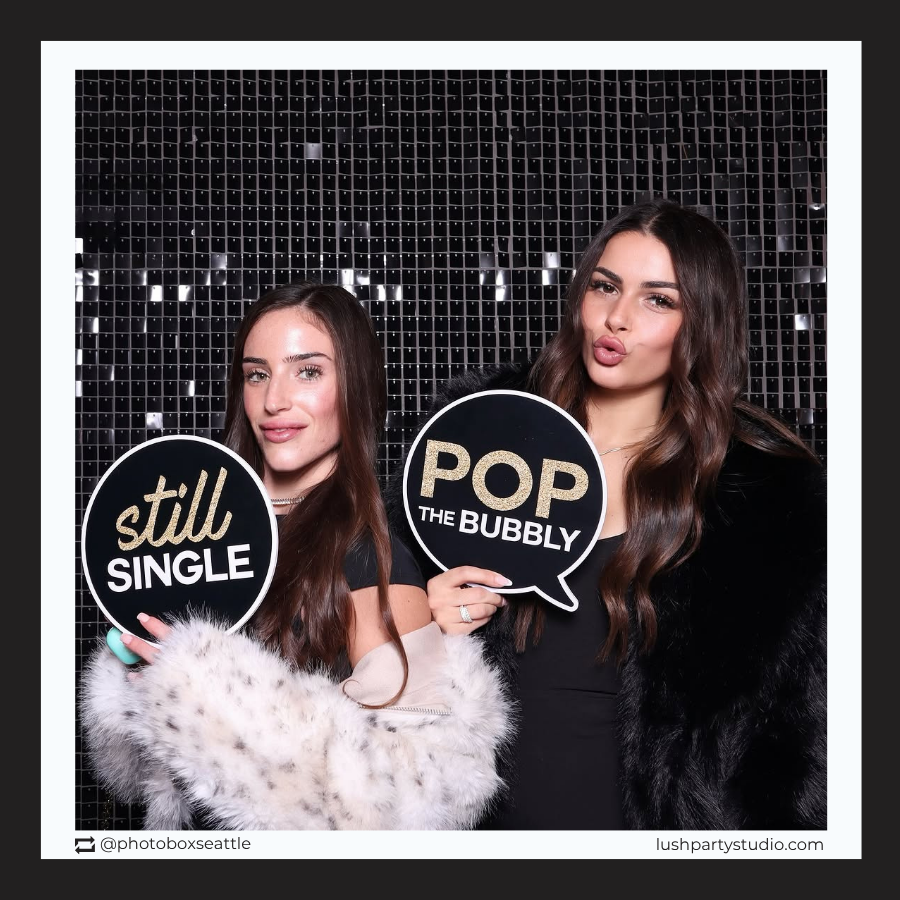 Two women holding wedding photo booth props by lush party studio
