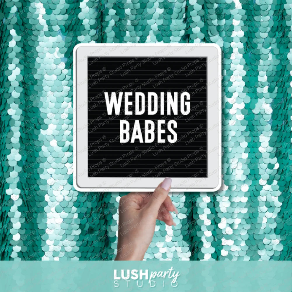 Hand holding a photo prop sign with 'Wedding Babes' text by Lush Party Studio branding.