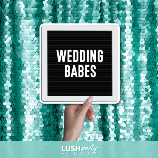 Hand holding a photo prop sign with 'Wedding Babes' text by Lush Party Studio branding.