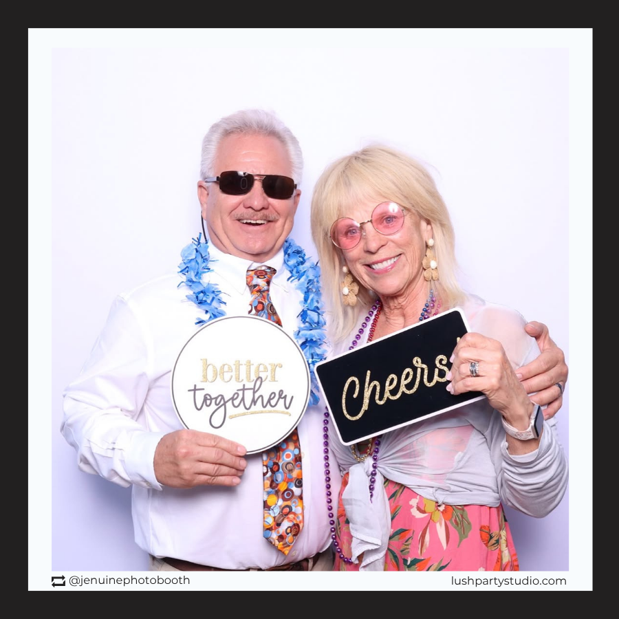 Two people holding photo booth prop signs with 'better together' and 'Cheers'  text