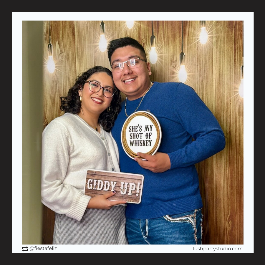 Two people holding signs with western theme photobooth props